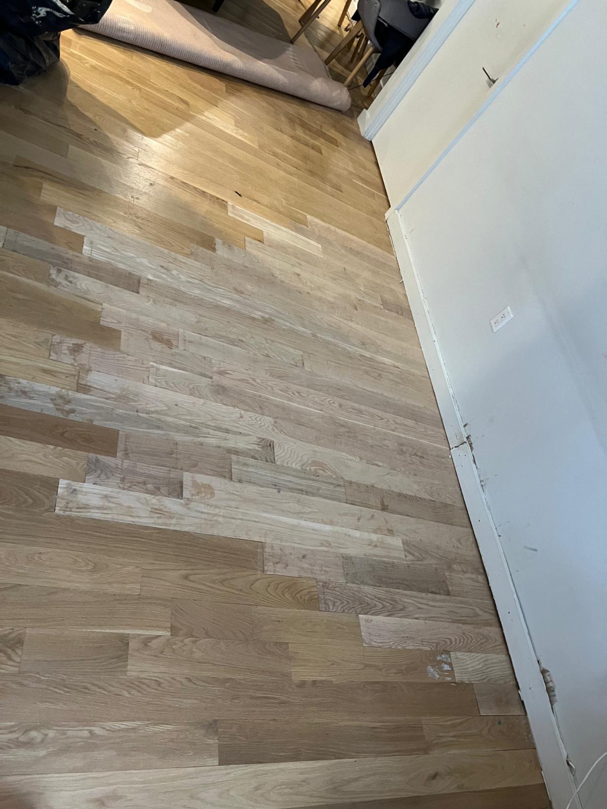 Newly installed unfinished hardwood floor running wall to wall