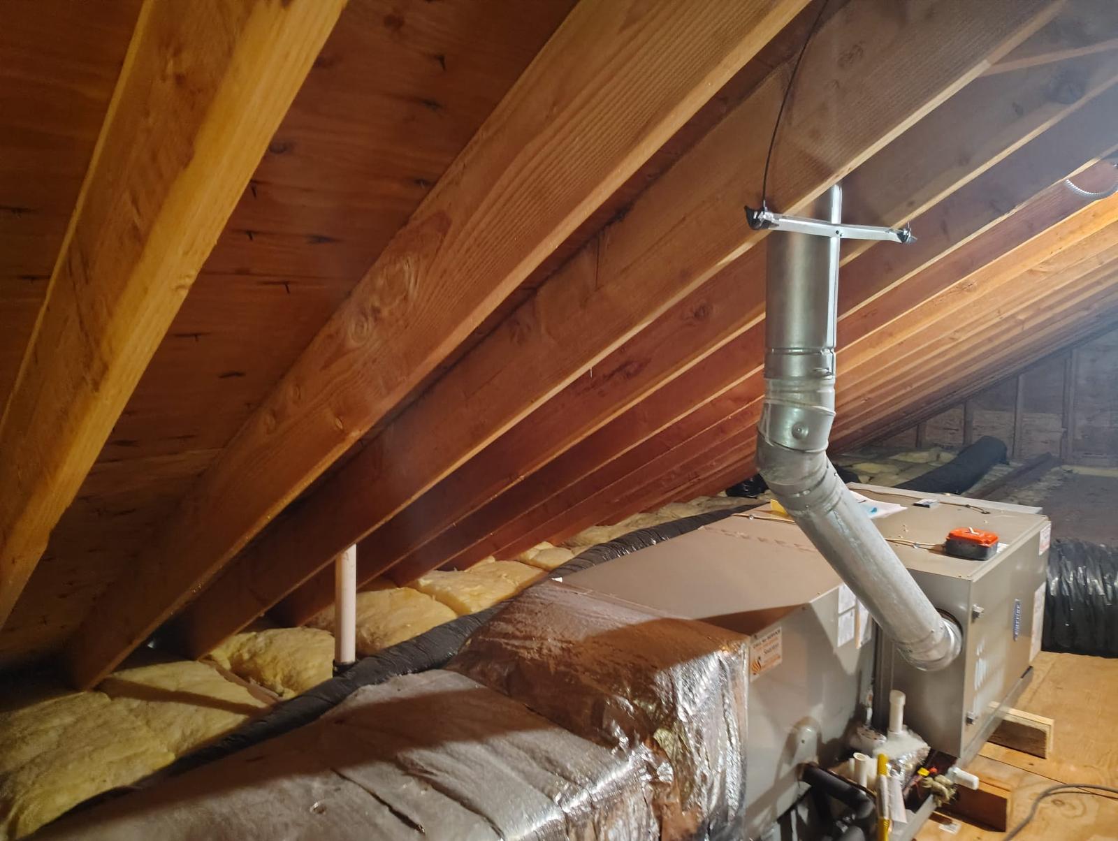 Attic before remediation with old insulation and HVAC unit