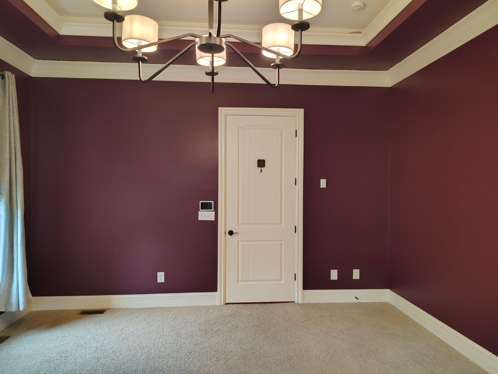 Room repainted in deep burgundy with white door and baseboards