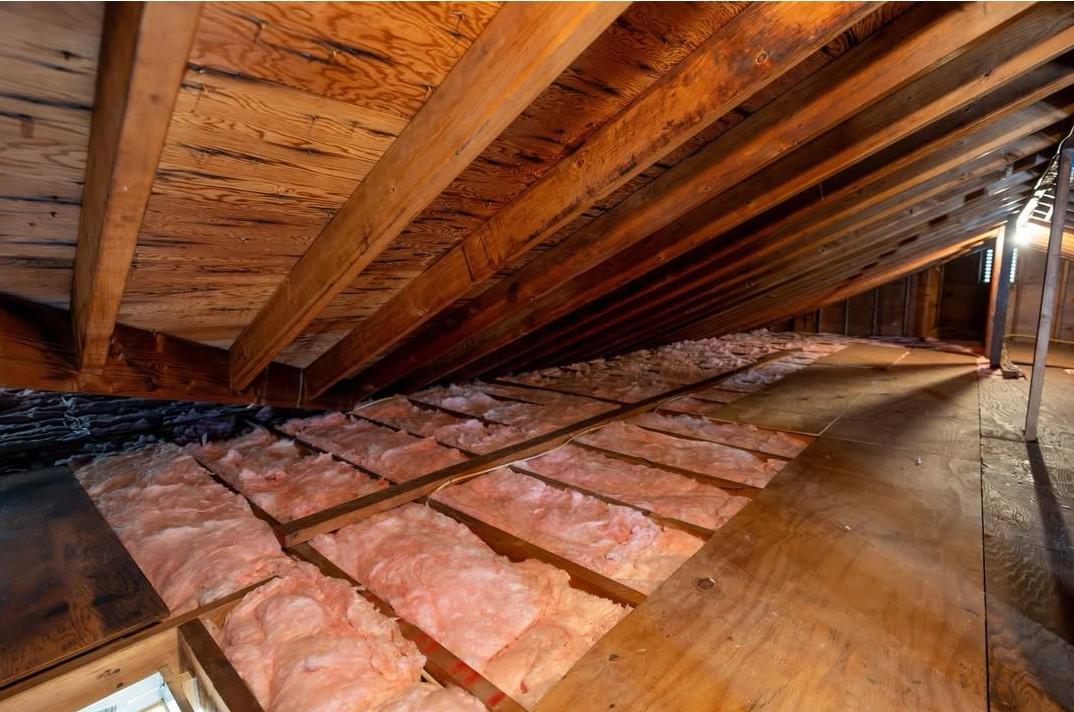 Clean attic with brand-new fiberglass insulation installed between joists